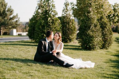 Gelin ve damat gün batımında parkta yürüyor.