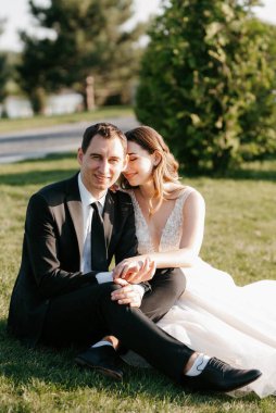 Gelin ve damat gün batımında parkta yürüyor.