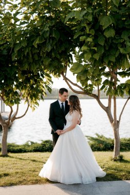 Gelin ve damat gün batımında parkta yürüyor.