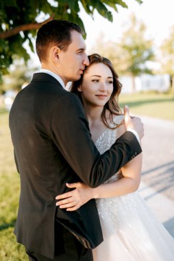 Gelin ve damat gün batımında parkta yürüyor.