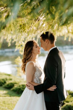 Gelin ve damat gün batımında parkta yürüyor.