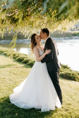 Gelin ve damat gün batımında parkta yürüyor.