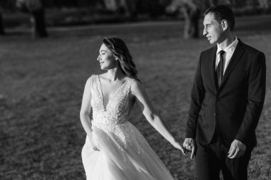 Gelin ve damat gün batımında parkta yürüyor.