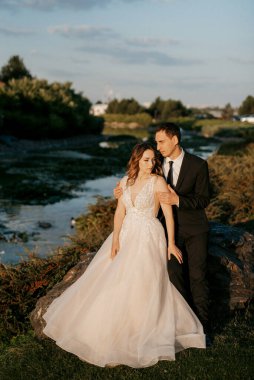 Gelin ve damat gün batımında parkta yürüyor.