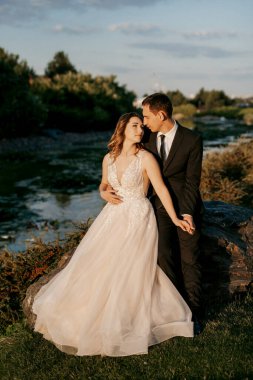 Gelin ve damat gün batımında parkta yürüyor.