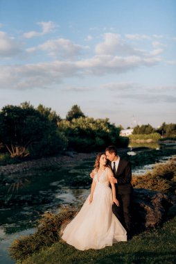 Gelin ve damat gün batımında parkta yürüyor.