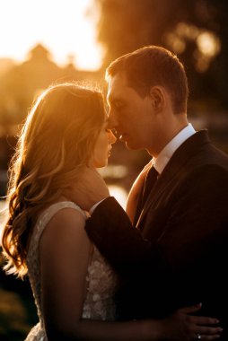 Gelin ve damat gün batımında parkta yürüyor.