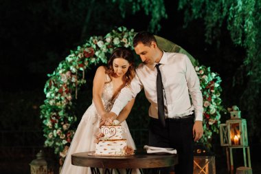 newlyweds happily cut, laugh and taste the wedding cake