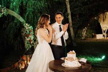newlyweds happily cut, laugh and taste the wedding cake