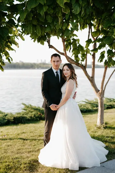 Gelin ve damat gün batımında parkta yürüyor.