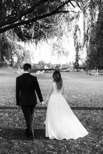 Gelin ve damat gün batımında parkta yürüyor.