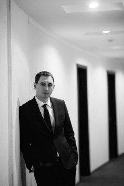 Siyah takım elbiseli ve kravatlı genç bir adamın portresi.