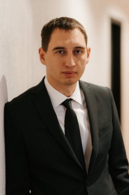 Siyah takım elbiseli ve kravatlı genç bir adamın portresi.