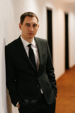 Siyah takım elbiseli ve kravatlı genç bir adamın portresi.