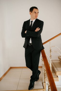 Siyah takım elbiseli ve kravatlı genç bir adamın portresi.