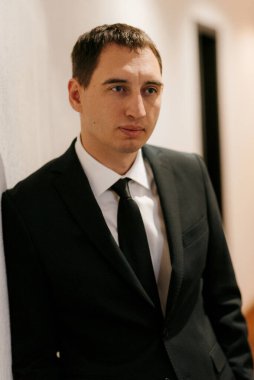 Siyah takım elbiseli ve kravatlı genç bir adamın portresi.