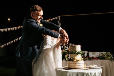 newlyweds happily cut, laugh and taste the wedding cake