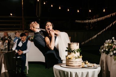 newlyweds happily cut, laugh and taste the wedding cake