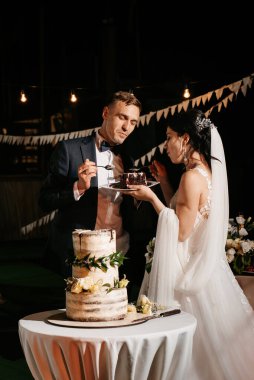 newlyweds happily cut, laugh and taste the wedding cake
