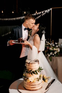 newlyweds happily cut, laugh and taste the wedding cake