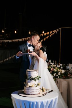 newlyweds happily cut, laugh and taste the wedding cake