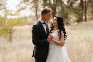 Genç bir çift, bir adam ve bir kız nehir kenarındaki yeşil tepeler boyunca yürüyorlar.