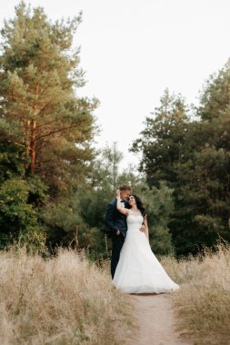 Genç bir çift, bir adam ve bir kız nehir kenarındaki yeşil tepeler boyunca yürüyorlar.