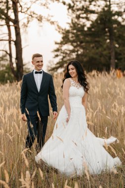 Genç bir çift, bir adam ve bir kız nehir kenarındaki yeşil tepeler boyunca yürüyorlar.