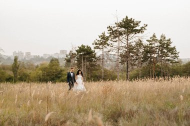 Genç bir çift, bir adam ve bir kız nehir kenarındaki yeşil tepeler boyunca yürüyorlar.