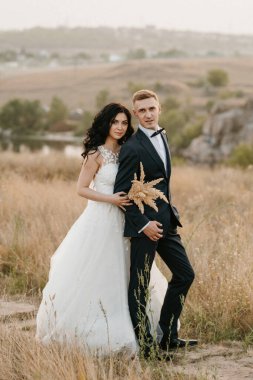 Genç bir çift, bir adam ve bir kız nehir kenarındaki yeşil tepeler boyunca yürüyorlar.