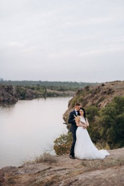 Genç bir çift, bir adam ve bir kız nehir kenarındaki yeşil tepeler boyunca yürüyorlar.