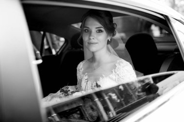 Gelin ve damat cam bir gökdelenin yanında siyah bir arabayla