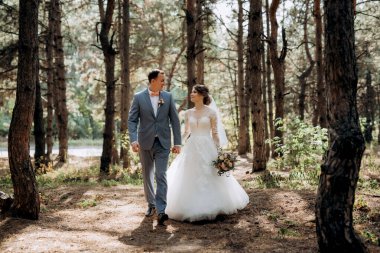 portrait of an elegant groom in a blue suit in a deciduous forest with a bouquet