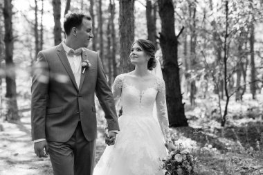 portrait of an elegant groom in a blue suit in a deciduous forest with a bouquet