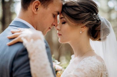 portrait of an elegant groom in a blue suit in a deciduous forest with a bouquet