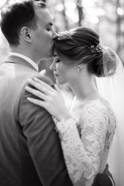 portrait of an elegant groom in a blue suit in a deciduous forest with a bouquet