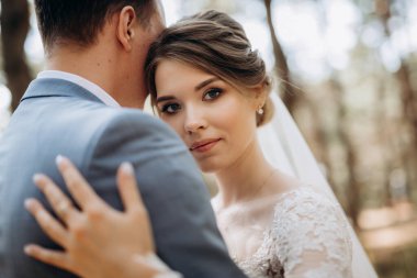 portrait of an elegant groom in a blue suit in a deciduous forest with a bouquet