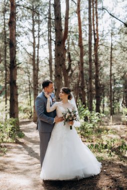 portrait of an elegant groom in a blue suit in a deciduous forest with a bouquet