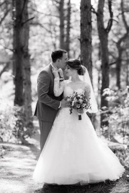 portrait of an elegant groom in a blue suit in a deciduous forest with a bouquet