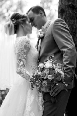 portrait of an elegant groom in a blue suit in a deciduous forest with a bouquet