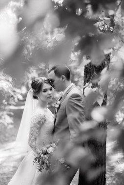 portrait of an elegant groom in a blue suit in a deciduous forest with a bouquet
