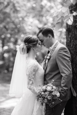 portrait of an elegant groom in a blue suit in a deciduous forest with a bouquet