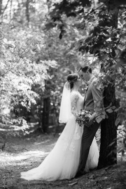 portrait of an elegant groom in a blue suit in a deciduous forest with a bouquet