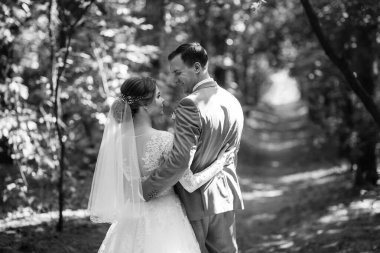 portrait of an elegant groom in a blue suit in a deciduous forest with a bouquet