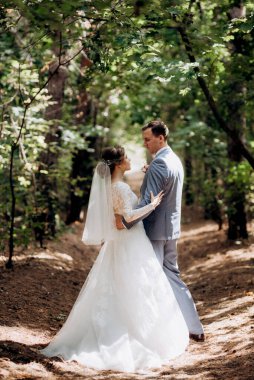 portrait of an elegant groom in a blue suit in a deciduous forest with a bouquet