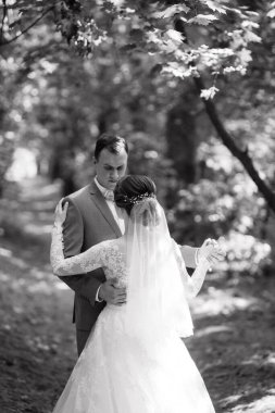 portrait of an elegant groom in a blue suit in a deciduous forest with a bouquet