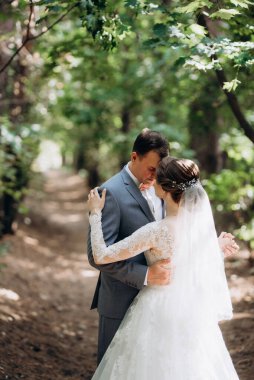portrait of an elegant groom in a blue suit in a deciduous forest with a bouquet