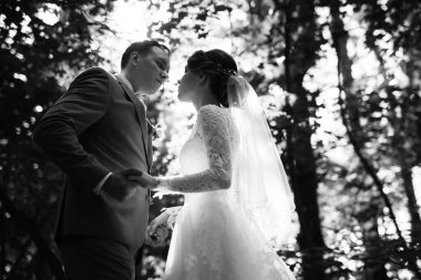 portrait of an elegant groom in a blue suit in a deciduous forest with a bouquet
