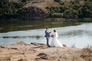 portrait of an elegant groom in a blue suit in a deciduous forest with a bouquet