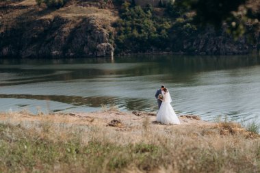 portrait of an elegant groom in a blue suit in a deciduous forest with a bouquet